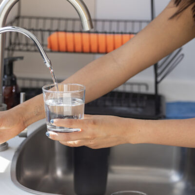 woman using an RO system to fill her glass of water from the tap